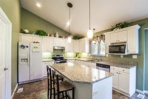 Large kitchen with white cabinets laminate counters and sage green walls